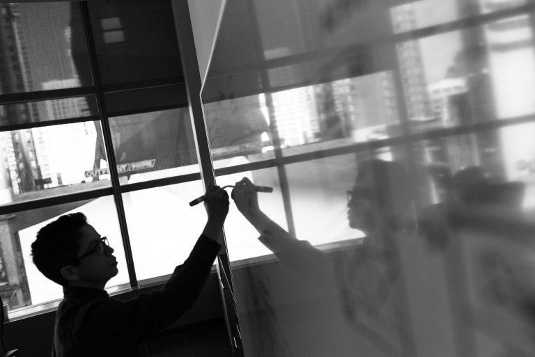 grayscale photo of man holding pen