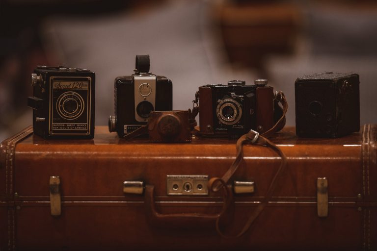 four assorted color cameras on brown suitfcase